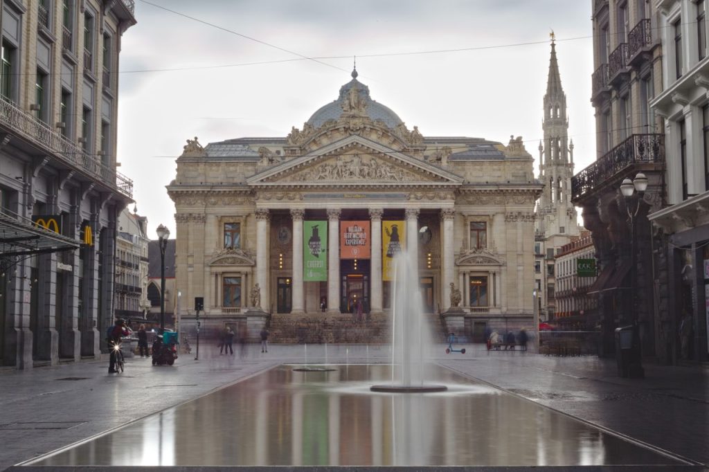 View of Brussels Stock Exchange with reflection pool and fountain, iconic architecture.