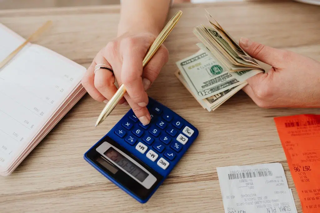 L’épargne de précaution : La clé de voûte de votre stabilité financière Hands handling cash and calculator for budget planning. Modern financial scene.